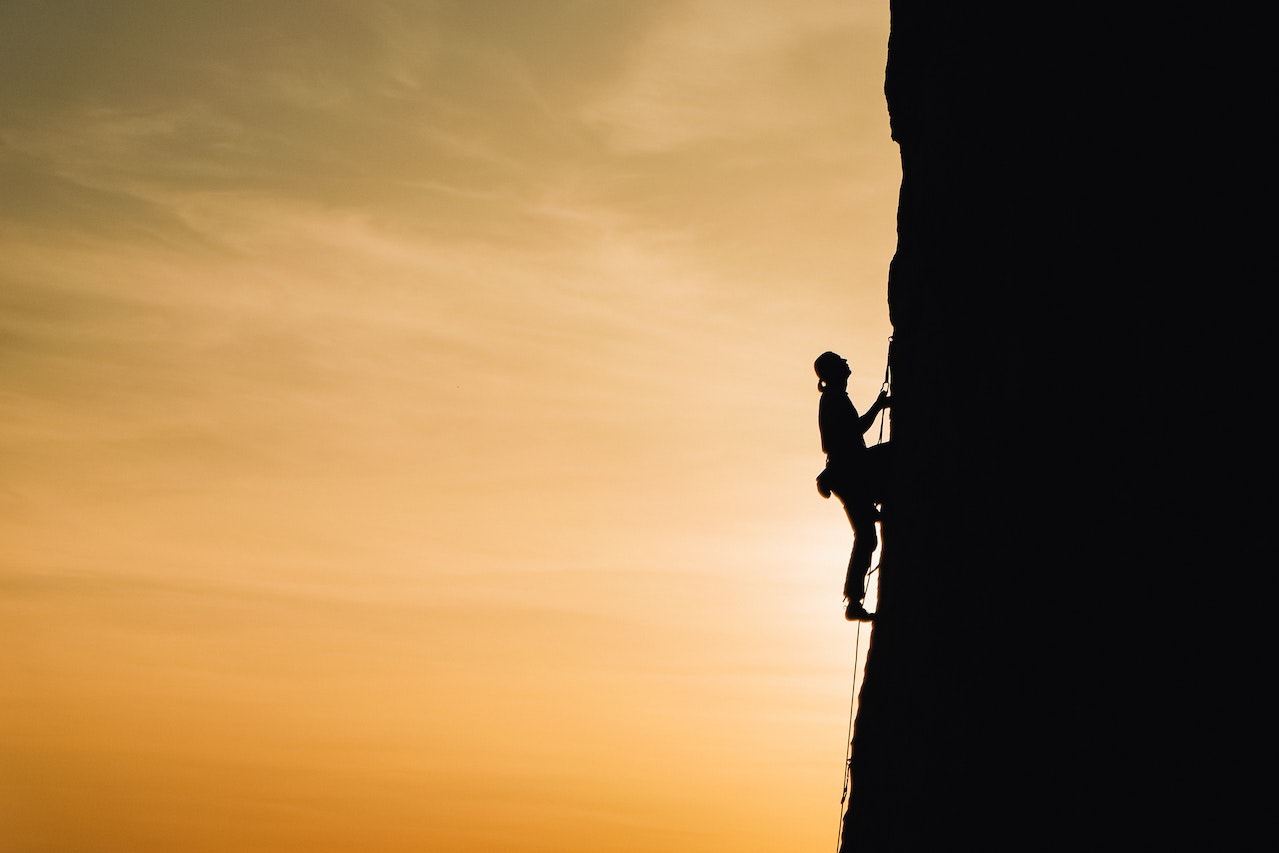 man climbing vertically a mountain